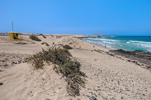 Una playa con una torre de salvavidas, dunas de arena y olas del océano.