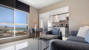 Ein modernes Wohnzimmer mit großem Fenster, Essbereich und Küche.