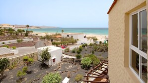 Blick auf die Küste mit Strand, einer Straße und einem Gebäude mit Balkon.