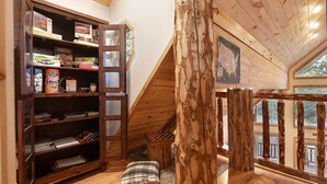 A wooden bookshelf filled with board games, a small stool, and a plaid pillow. - Pet Friendly | EV Charger| Zion/Bryce Hub | Family Fun (Duck Creek Village)