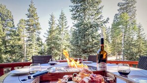 An outdoor dining area with a fire feature, a bottle of wine, and a charcuterie board. - Pet Friendly | EV Charger| Zion/Bryce Hub | Family Fun (Duck Creek Village)