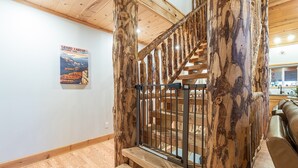 A wooden staircase with a metal railing, a poster on the wall, and a leather couch in the background. - Pet Friendly | EV Charger| Zion/Bryce Hub | Family Fun (Duck Creek Village)