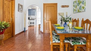 Un coin repas avec une table en bois, des chaises et une cuisine en arrière-plan.