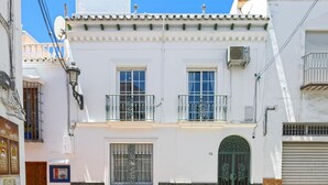Un immeuble de deux étages doté d’un balcon, d’une porte verte et d’une antenne parabolique.