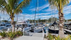 A marina with multiple boats docked, palm trees, and a wooden walkway. - 3BR Townhouse (Merritt Island)