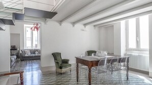 Uma sala de estar ampla com uma mesa de jantar, cadeiras, um sofá e um candelabro.
