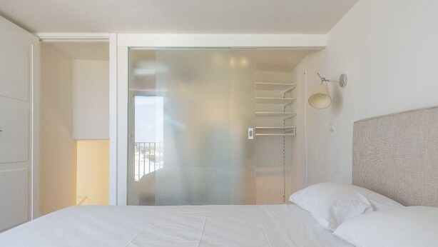 Quarto de hotel com cama, armário e vista para o exterior.
