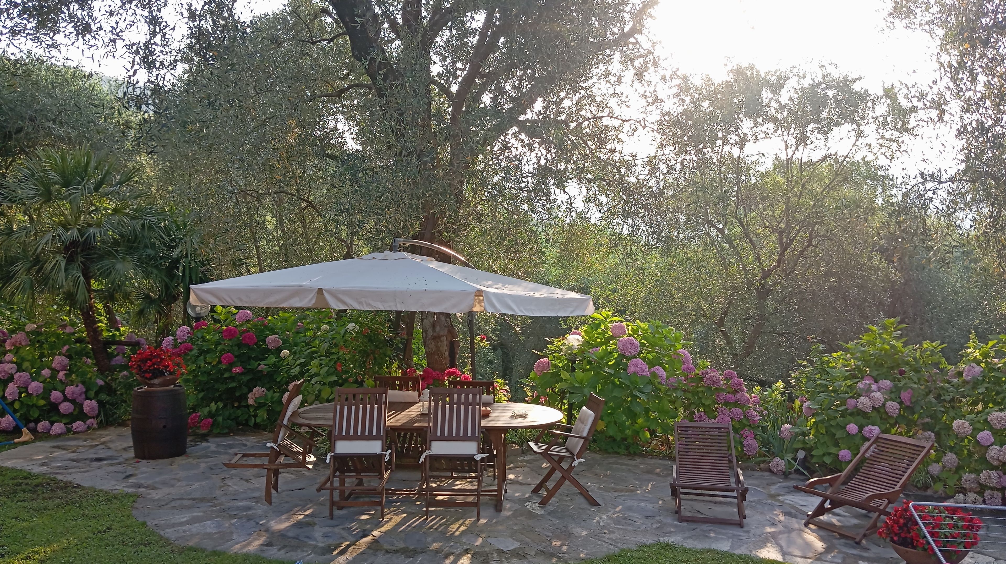 An outdoor patio with a round table, wooden chairs, and a white umbrella.