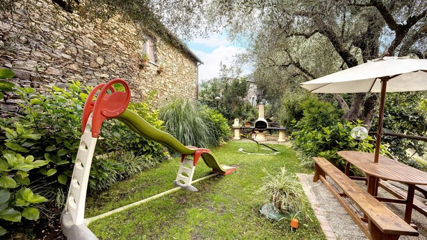 A garden with a stone wall, a wooden bench, and a swing set.