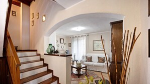 A staircase leading to a living area with a white sofa, a coffee table, and a plant.