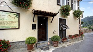 A building with a signboard, a door, and potted plants.