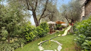 A garden with a circular stone path, a children's play area with a slide, and a picnic table under an umbrella.