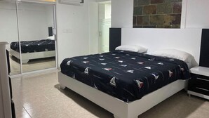 A bedroom with a bed, a wardrobe, a nightstand, and a wall-mounted TV.