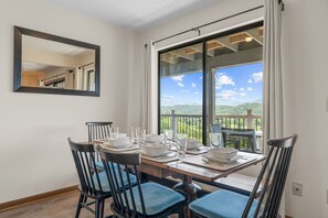 Ein Essbereich mit einem Tisch für vier Personen, Stühlen, einem großen Fenster mit Blick und einem Spiegel an der Wand.