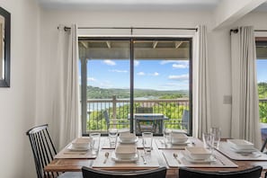 A dining area with a table set for four, overlooking a scenic view of a lake and greenery. - Amazing Lake View Walk-In Condo, Newly Renovated Spacious Near Silver Dollar City with Free Tickets (Branson)