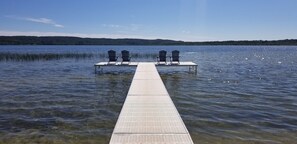 A pier extending into calm water with two Adirondack chairs at the end. - Lakefront Cottage #5, AC, Newly Remodeled, 8 Kayaks, 4 SUP, Rowboats (Frankfort)