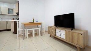 Uma cozinha moderna com armários brancos, uma mesa de jantar de madeira e uma TV em um móvel de madeira.