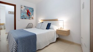 Quarto com cama, mesa de cabeceira, luminária e um painel com um letreiro.