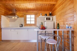 A wooden interior with a kitchen area, including a microwave, coffee maker, and a window.