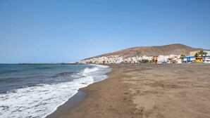 A beach with a sandy shore, a clear sky, and buildings in the background. - Holiday home La Cabañita de Javi with Sea View, Garden & Wi-Fi (Tuineje)