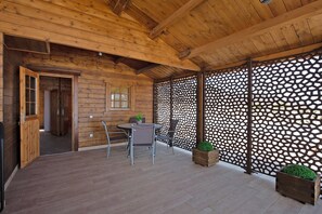 A wooden cabin interior with a dining area, a wooden door, and a decorative lattice wall.