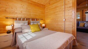 A wooden cabin bedroom with a bed, nightstands, and a night lamp. - Holiday home La Cabañita de Javi with Sea View, Garden & Wi-Fi (Tuineje)
