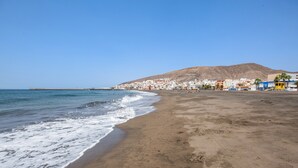 Una spiaggia con vista libera sull'oceano, una riva sabbiosa e una città sullo sfondo.