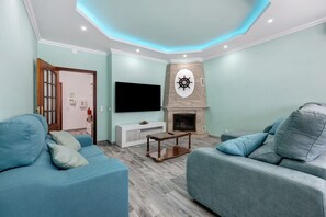 A living room with a flat-screen TV, a fireplace, and two sofas. - Apartment Casa Violeta with Terrace, A/C & Wi-Fi (Lagos)