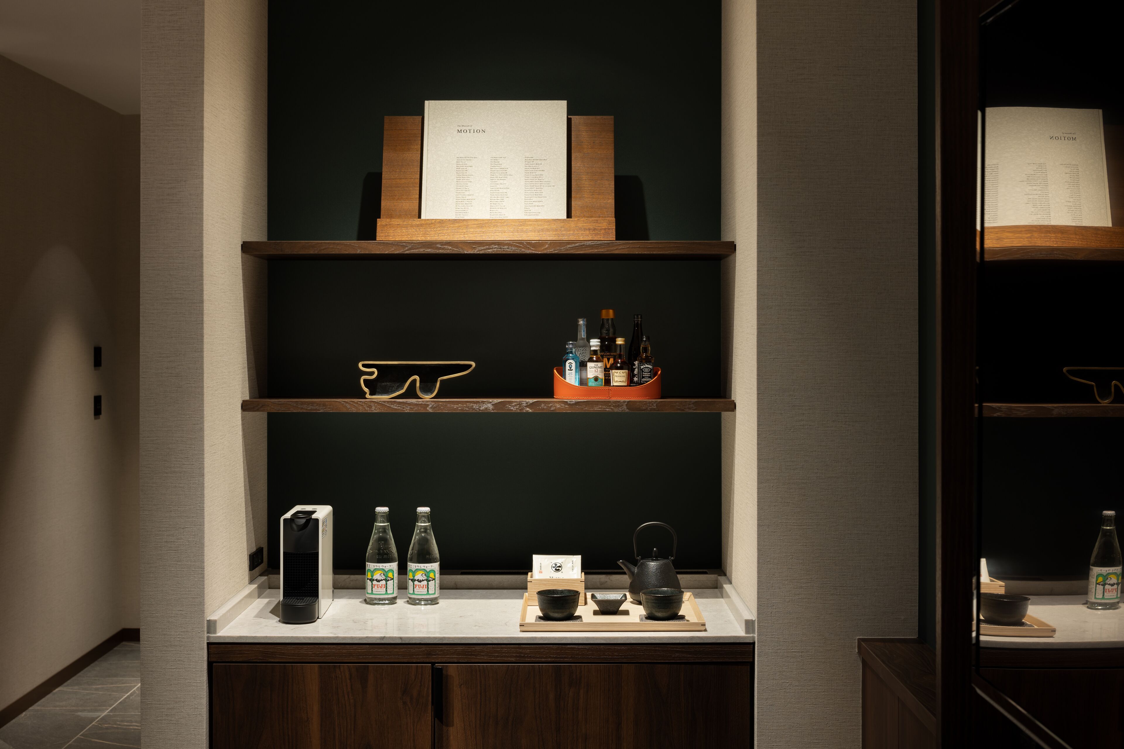 A reception area with a wooden reception desk, a menu board, and a display of bottled beverages and tea sets.