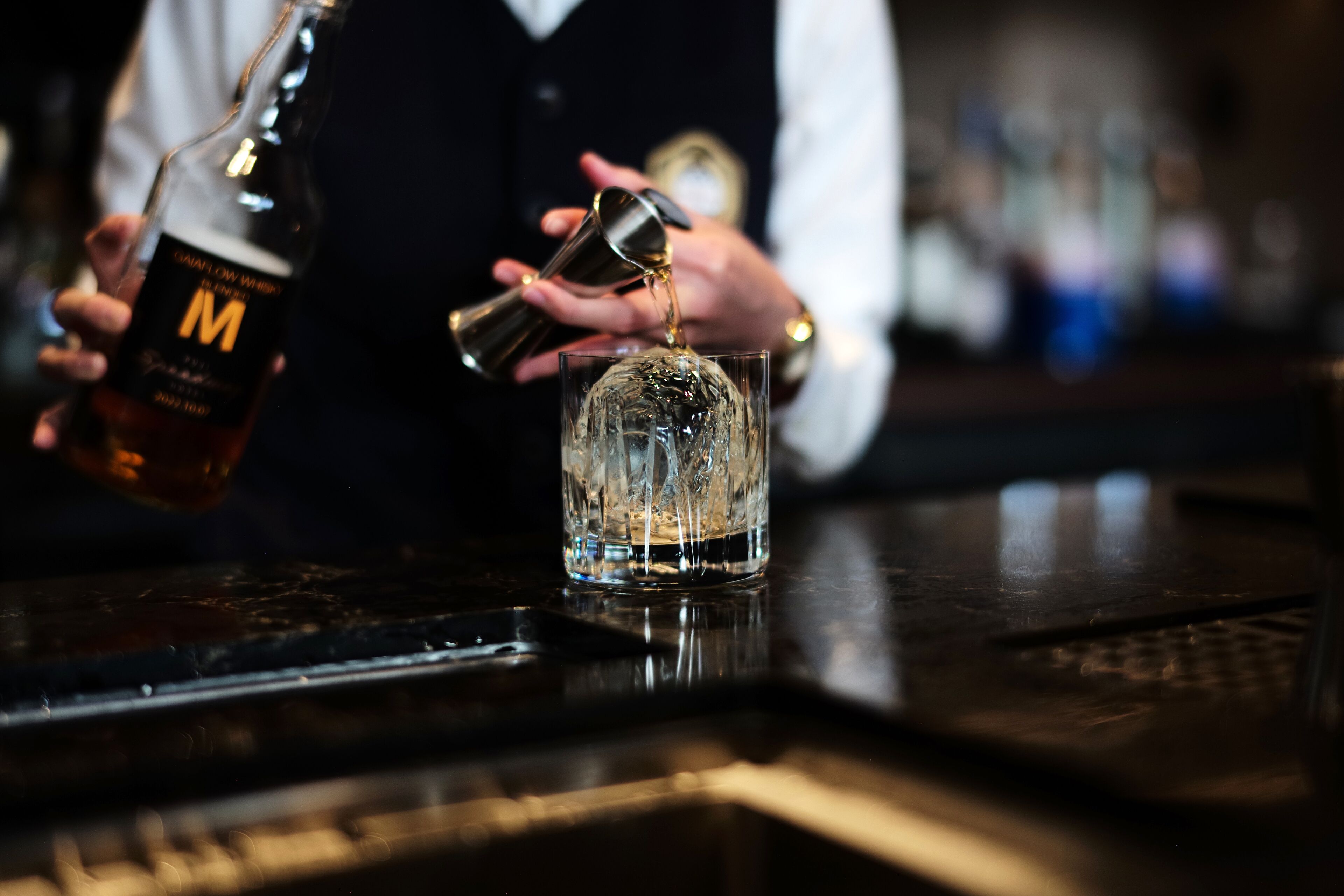 Iemand giet een drankje in van een fles in een glas.
