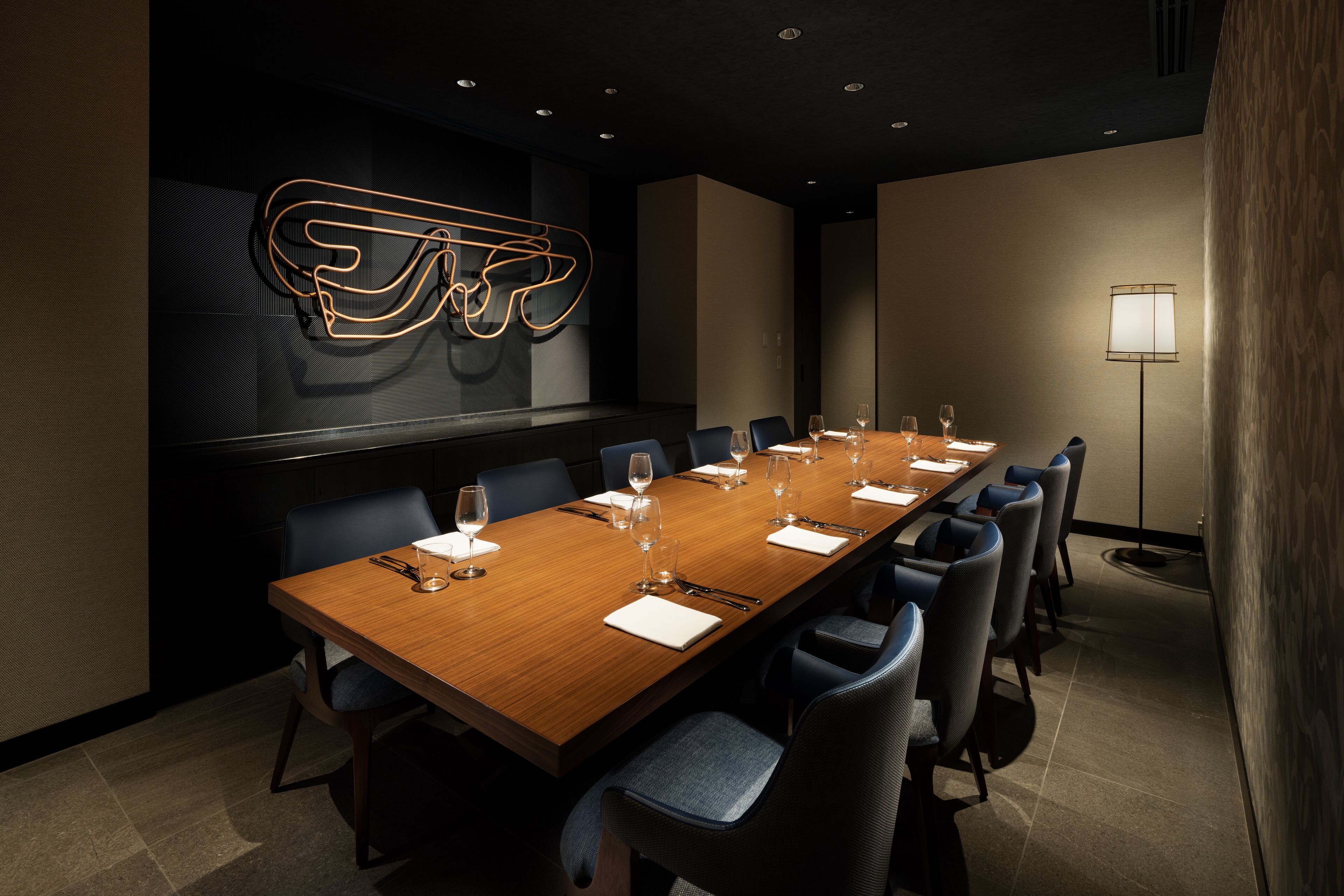 A conference room with a long wooden table, blue chairs, and a modern abstract light fixture on the wall.