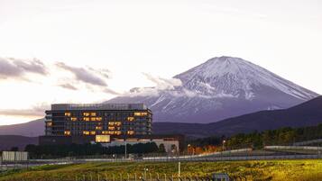 Un hotel moderno con varios pisos, techo plano y vista a una montaña nevada en el fondo.