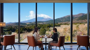 Un espace repas doté de grandes fenêtres donnant sur un paysage montagneux.