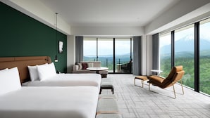 Une chambre d’hôtel avec un grand lit, un canapé, une petite table et une chaise. Elle dispose d’un balcon avec vue sur une montagne.