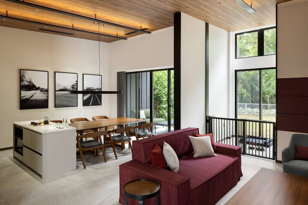 A modern interior with a dining area, kitchen, and seating space with large windows.