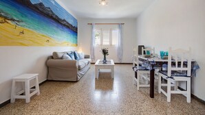Una sala de estar con un cuadro, un sofá, una mesa de centro y un comedor con sillas y una mesa.