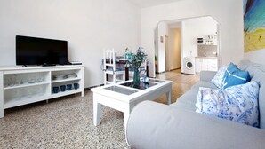 Una sala de estar con sofá, mesa de centro, televisor y estanterías con vasos.
