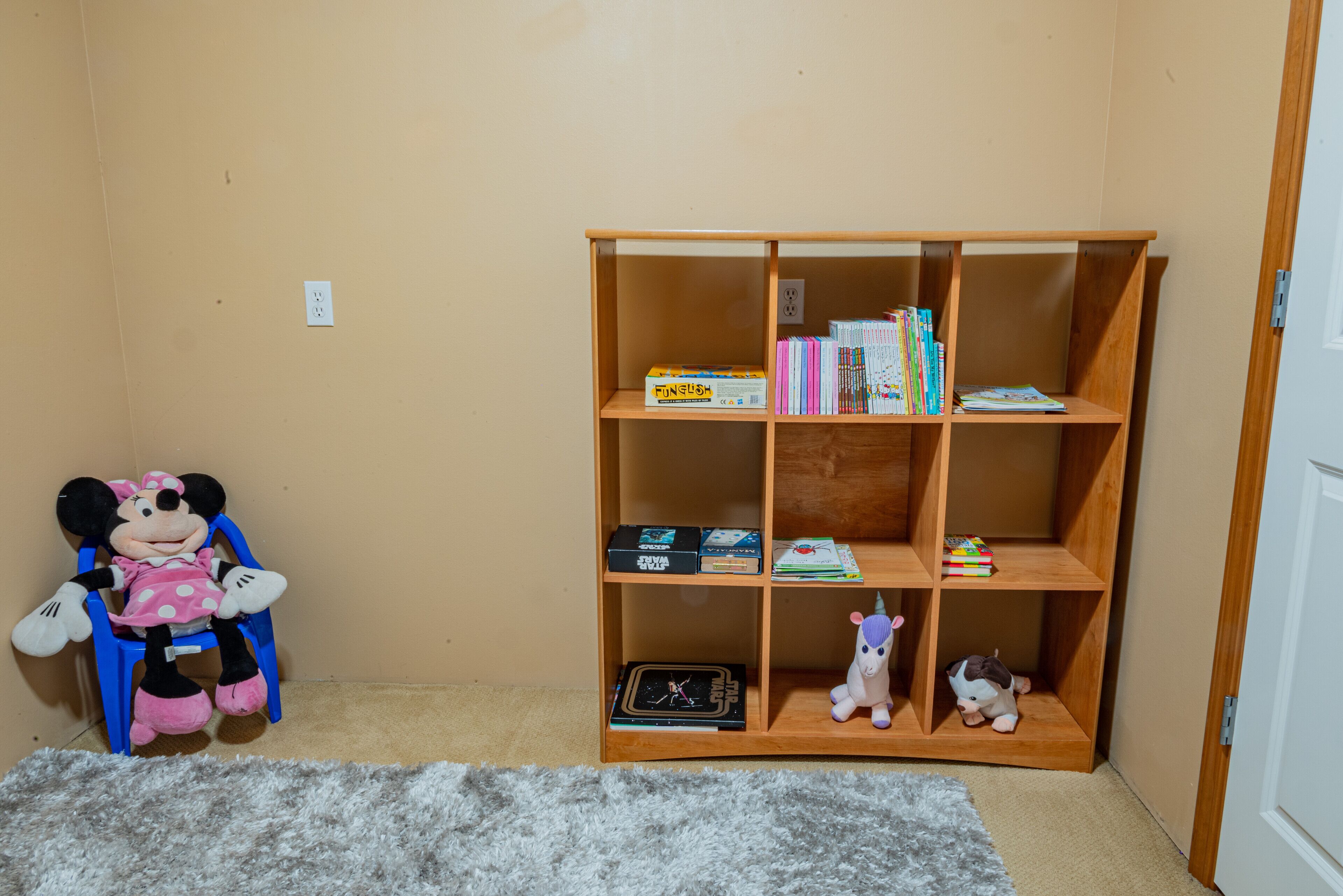 A room with a wooden bookshelf containing books and a plush toy.