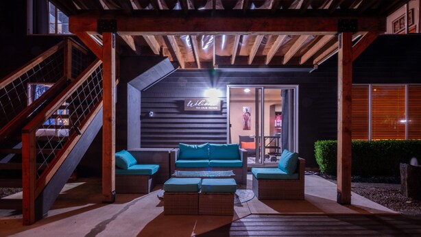 A wooden deck with a sofa and ottoman set, a staircase, and a sign reading "Welcome to our home". - Home: Sleeps 4, Bedroom, Living, Bath, Office, Patio (Bothell)