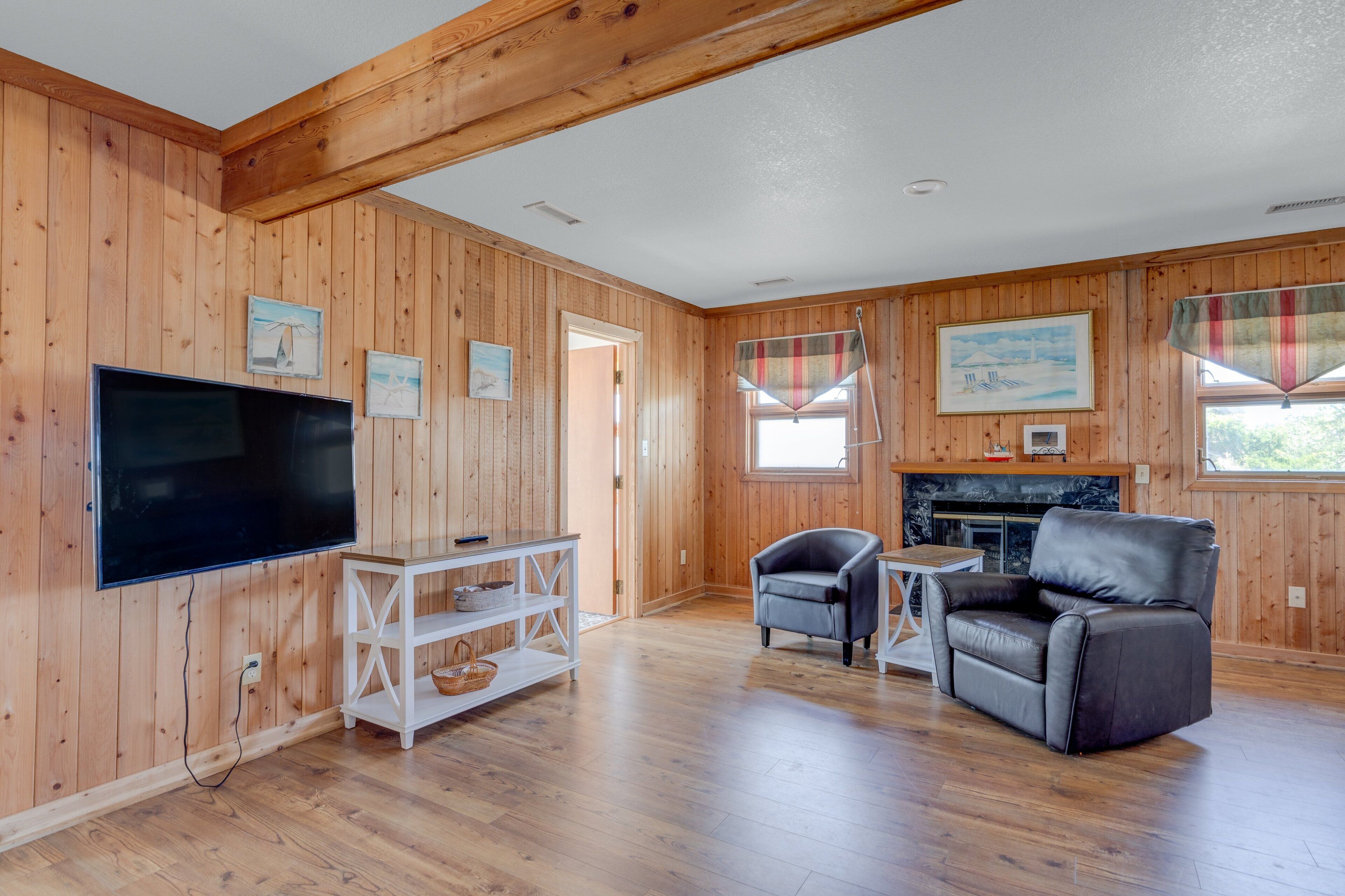 A wooden-paneled room with a flat-screen TV, a fireplace, a sofa, and a small table.