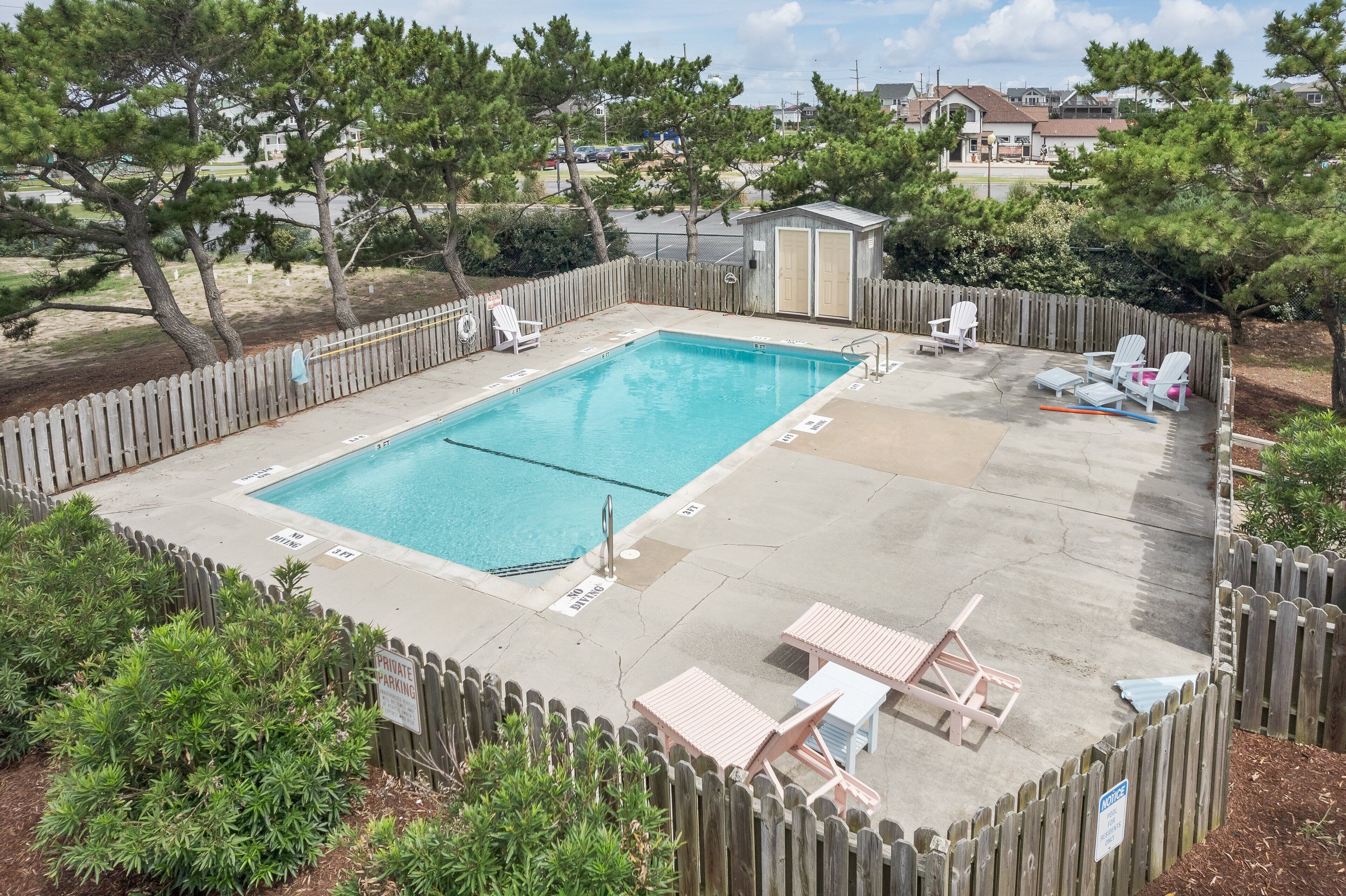 A rectangular pool with two lounge chairs and a small shed in the background.