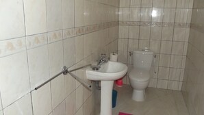 Ein Badezimmer mit weißem Waschbecken, Toilette und gefliesten Wänden.