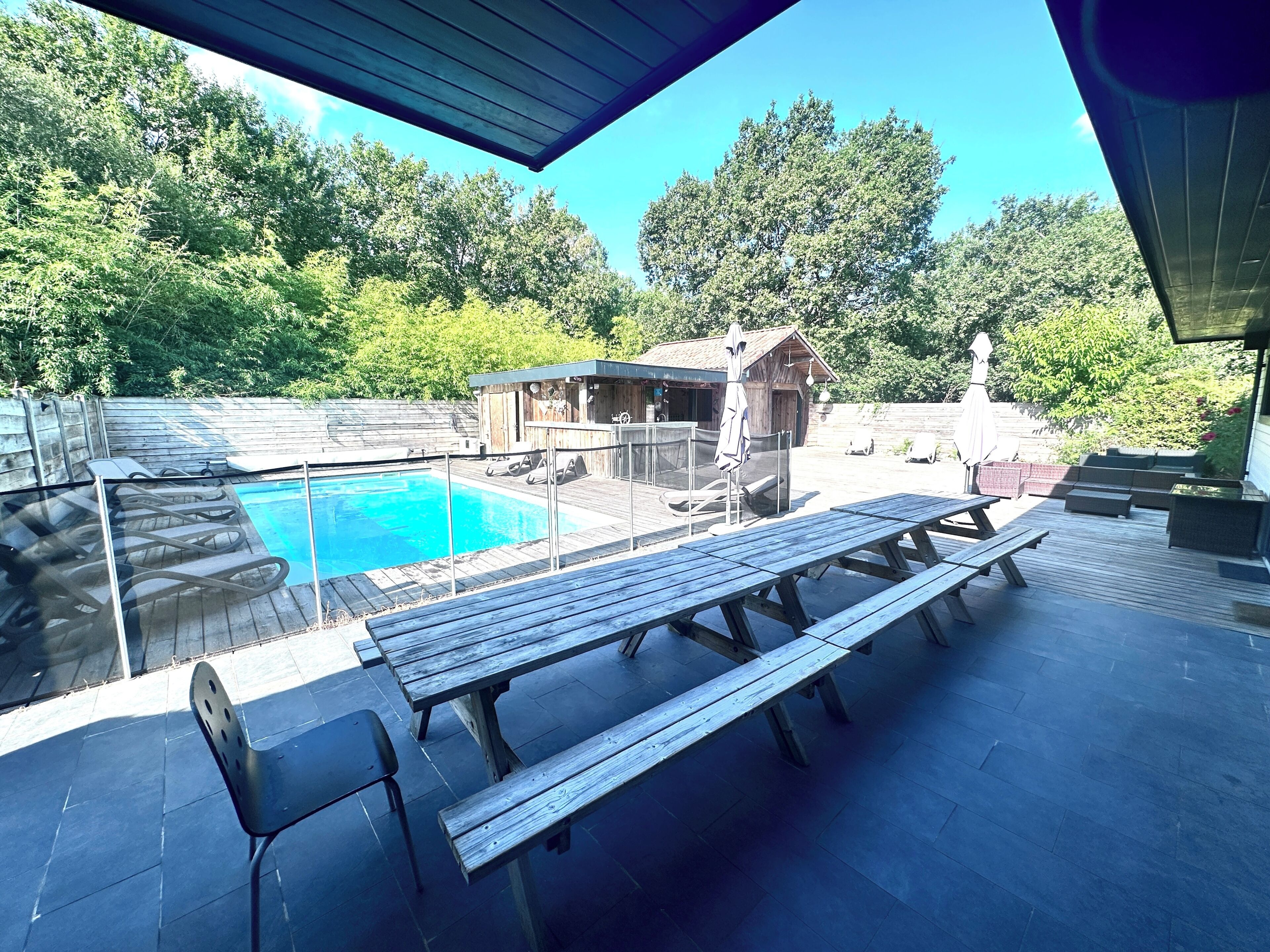 Un área de piscina con cubierta de madera, sillas de descanso y un jacuzzi.