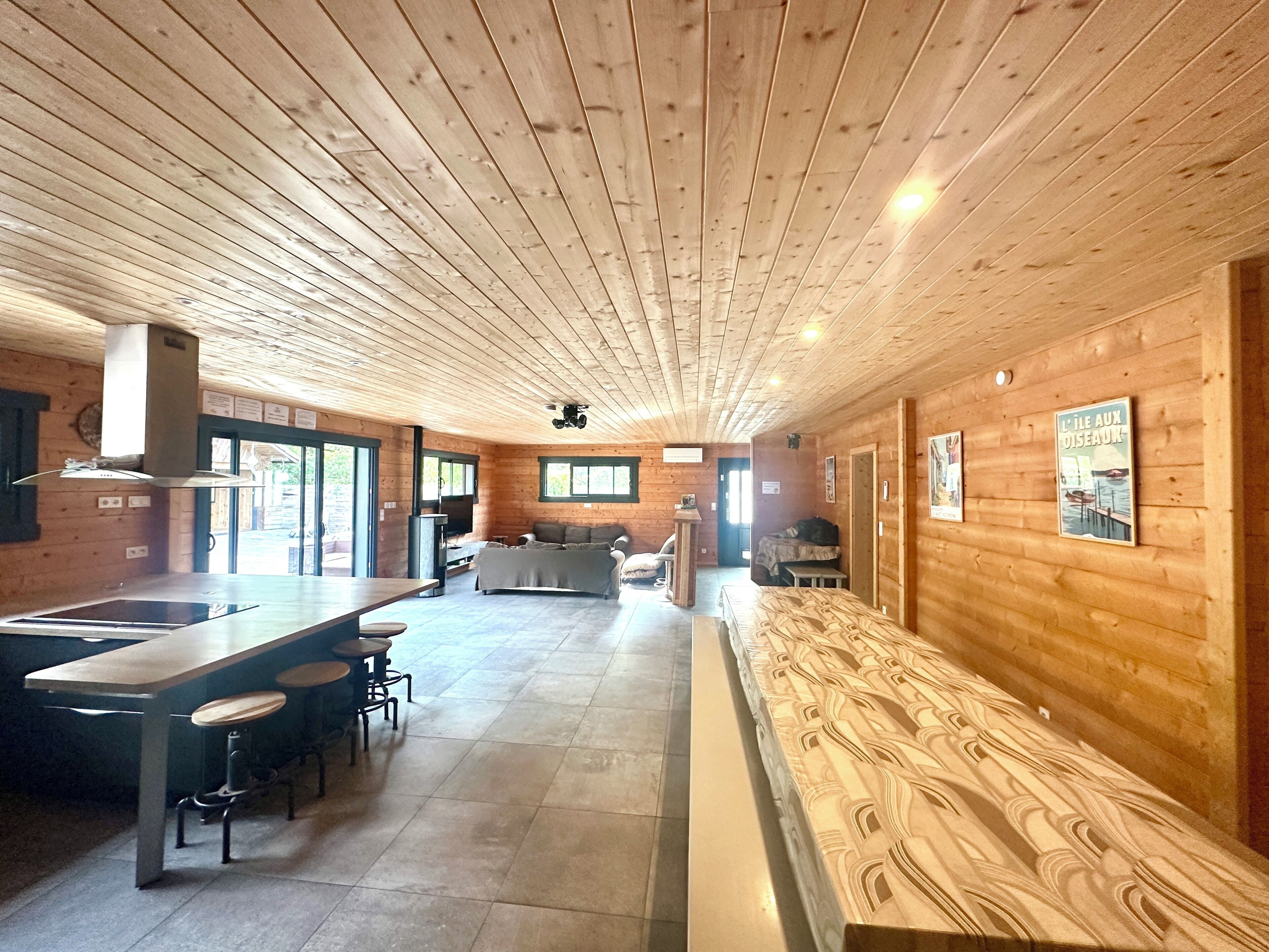 Interior em madeira com cozinha, espaço para refeições e um banco.