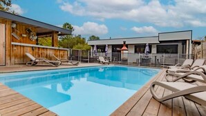 A swimming pool with lounge chairs and a wooden deck.