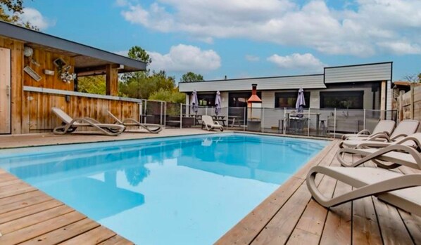 A swimming pool with lounge chairs and a wooden deck.