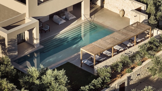 Une maison moderne dotée d’une piscine, d’un espace salon extérieur et d’une terrasse en pierre.