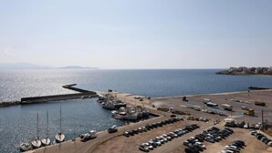 A coastal marina with boats docked, a parking area, and a clear view of the sea and distant land. - Apartment in Rafina with Garden & BBQ (Rafina)