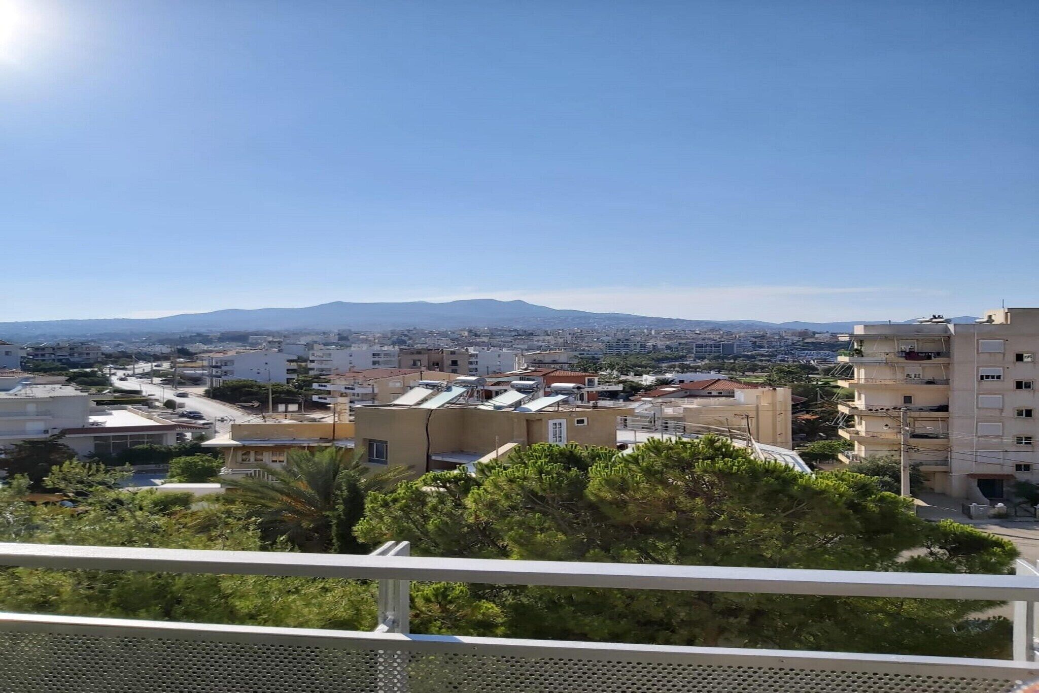 A residential area with buildings, a clear sky, and distant mountains.