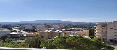 A residential area with buildings, a clear sky, and distant mountains.